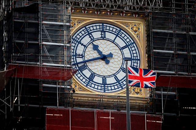 A Union Jack flag flutters in the breeze in front of the clock face of the Elizabeth Tower