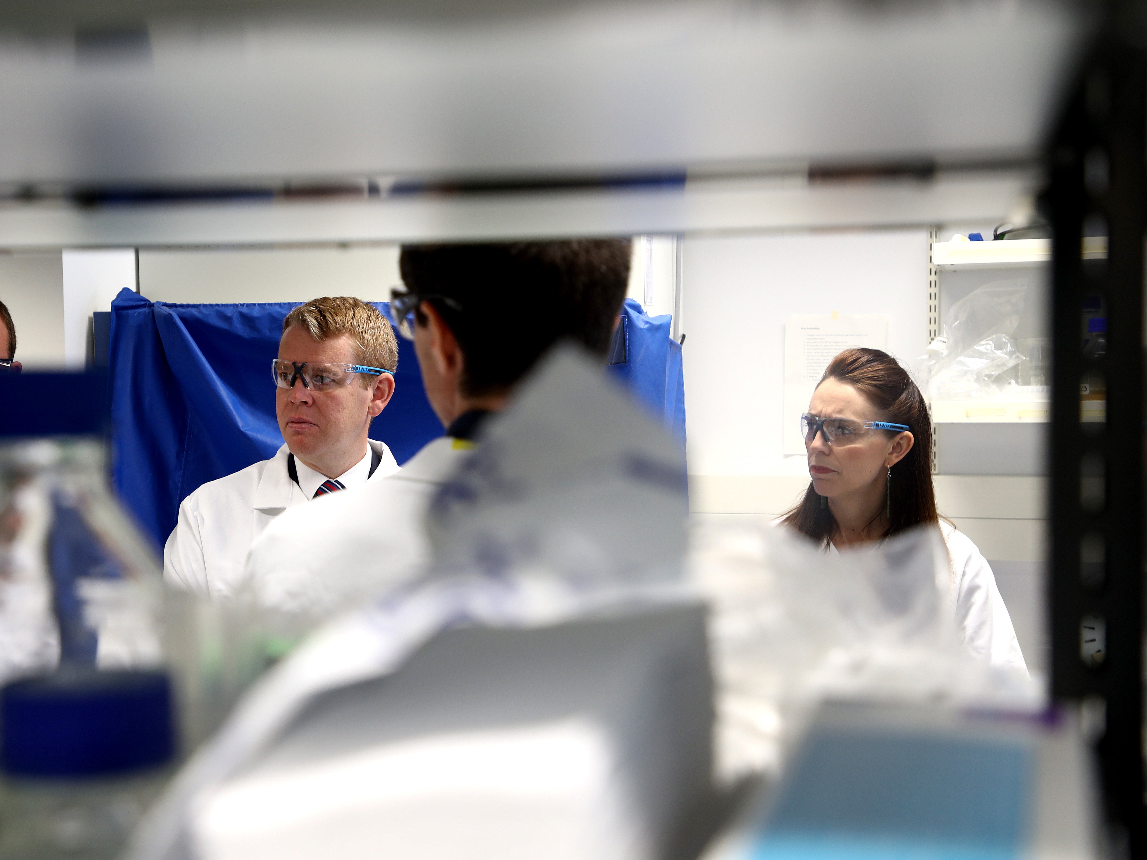 Jacinda Ardern and Covid-19 response minister Chris Hipkins visit a lab at Auckland University after announcing they have secured enough vaccine doses to immunise the whole population