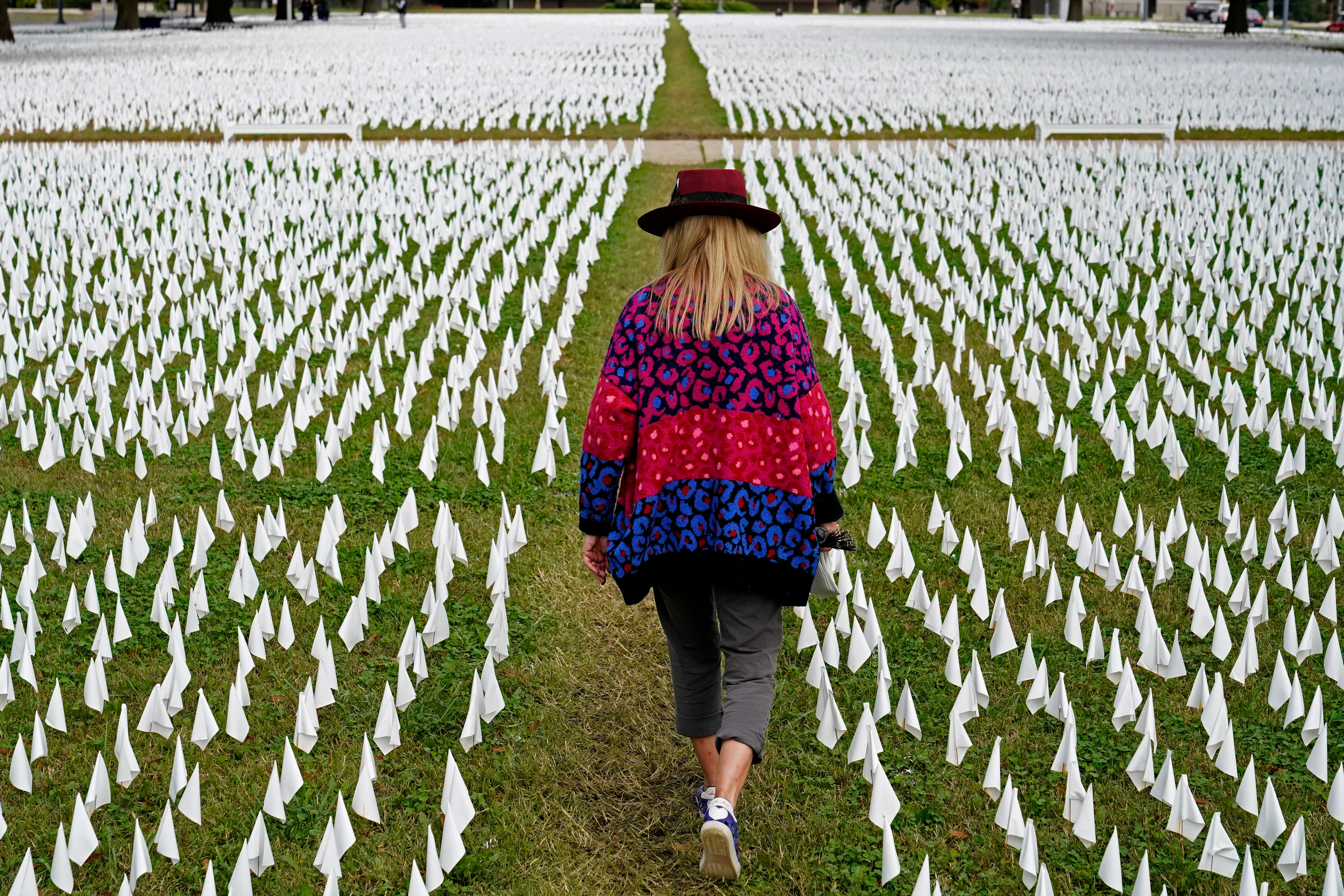 Artist Suzanne Brennan Firstenberg walks among thousands of white flags planted in remembrance of Americans who have died of Covid-19 in Washington DC. The U.S. death toll from the coronavirus topped 300,000 on 14 December as the first doses of a vaccine became available.
