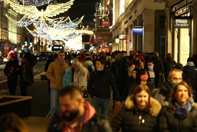Shoppers walk under the Christmas lights on Regents Street in London on December 6, 2020