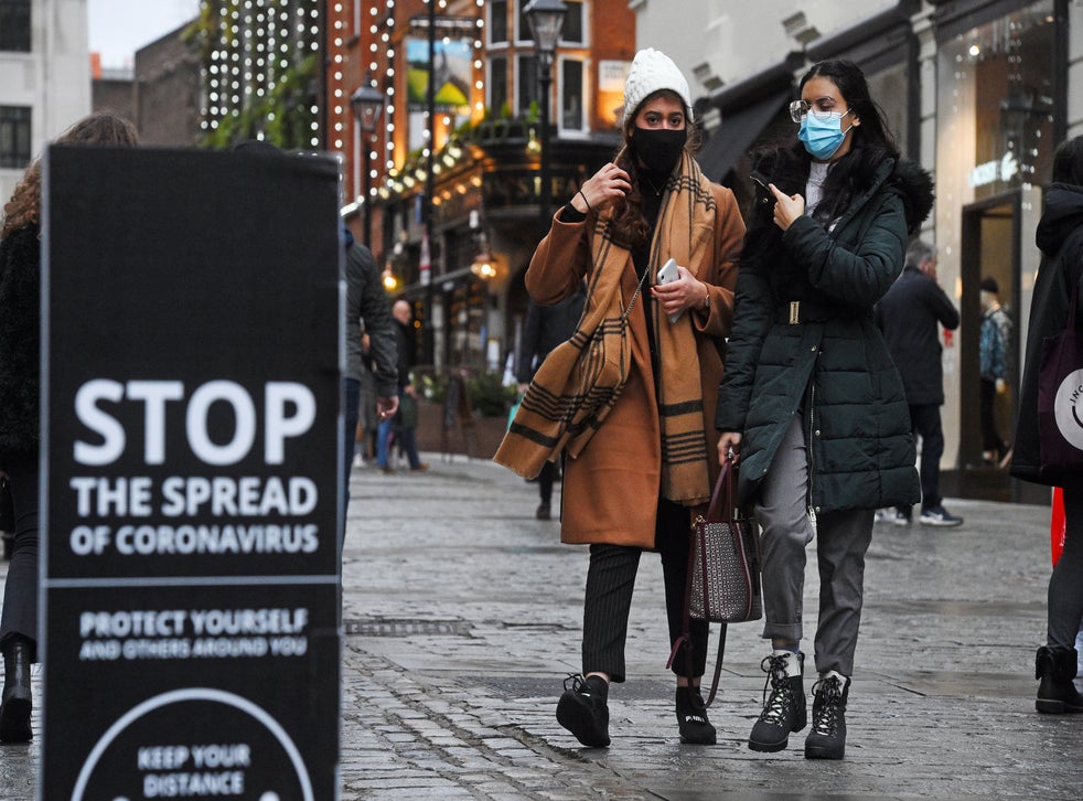 <p>People walk past a sign advising social distancing in Covent Garden in London on Friday</p>