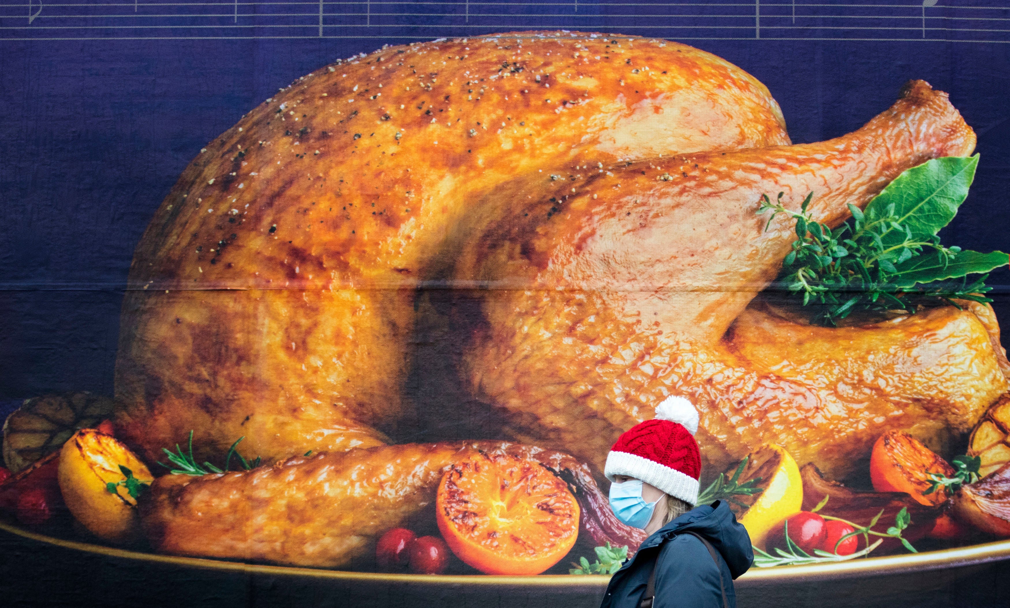 A shopper passes a billboard poster featuring a Christmas turkey in Edinburgh city centre