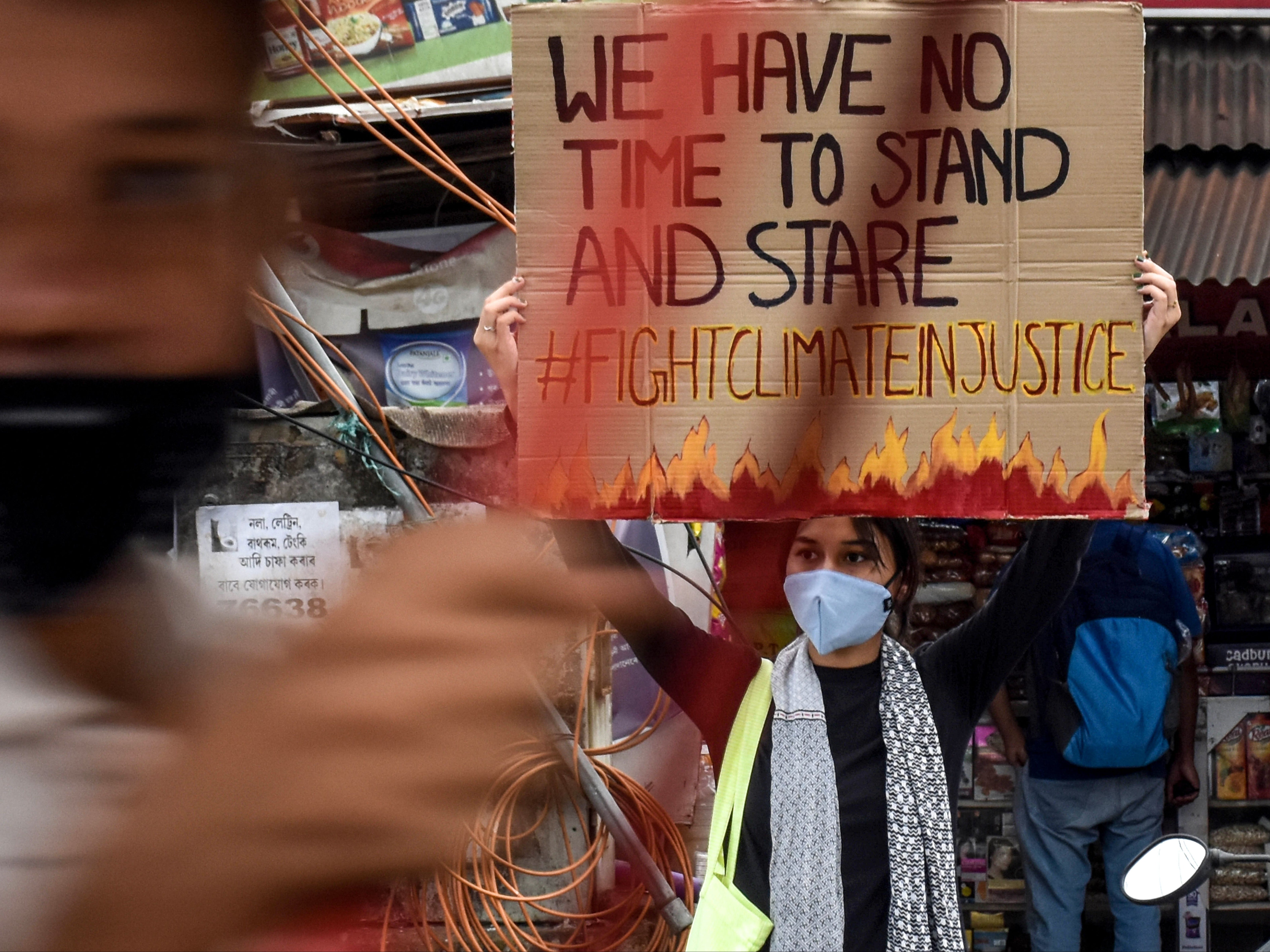 A youth Fridays for Future activist in Guwahati, India, holds a sign reading "#fightclimateinjustice”