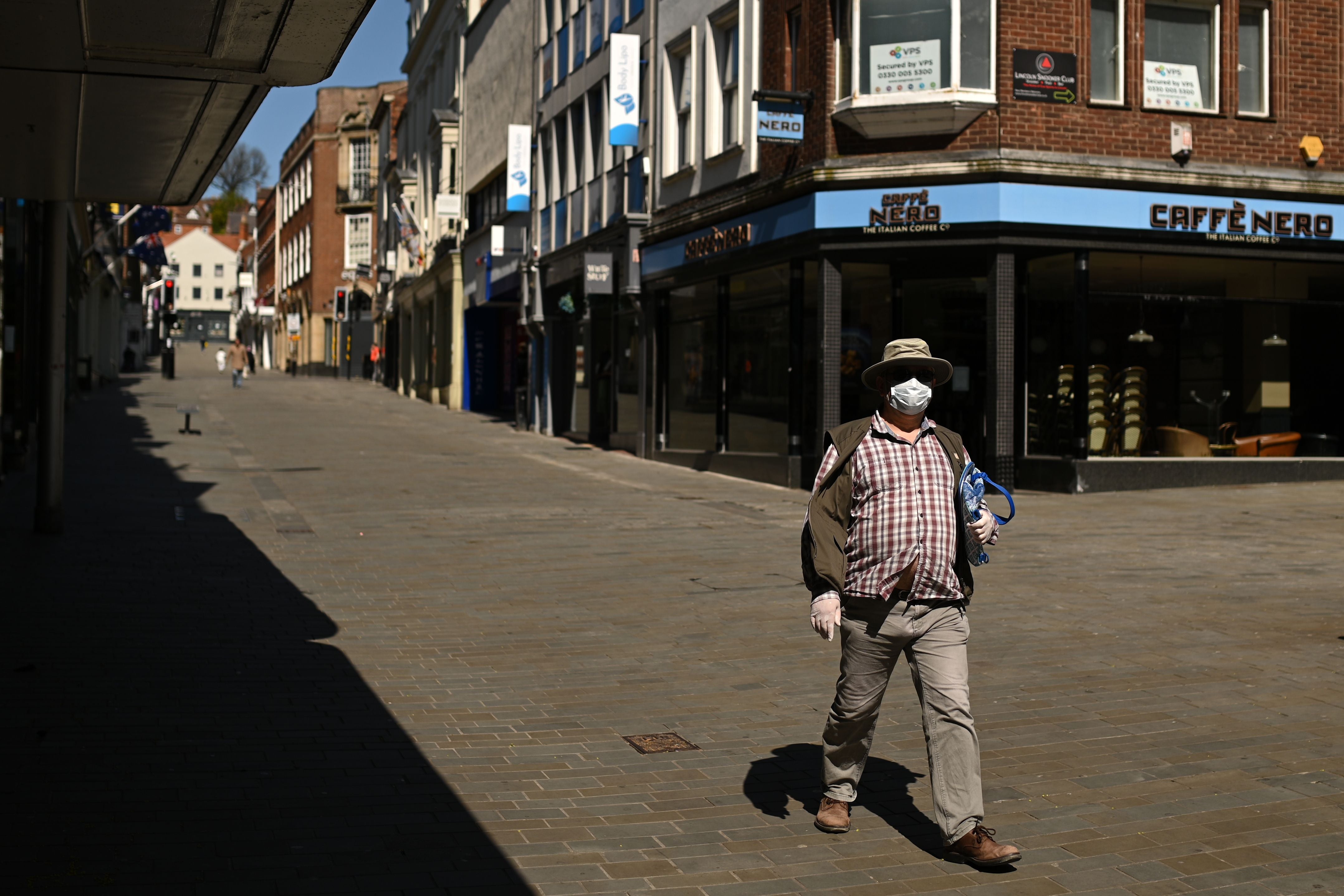 A man wears a protective face mask as he walks through Lincoln
