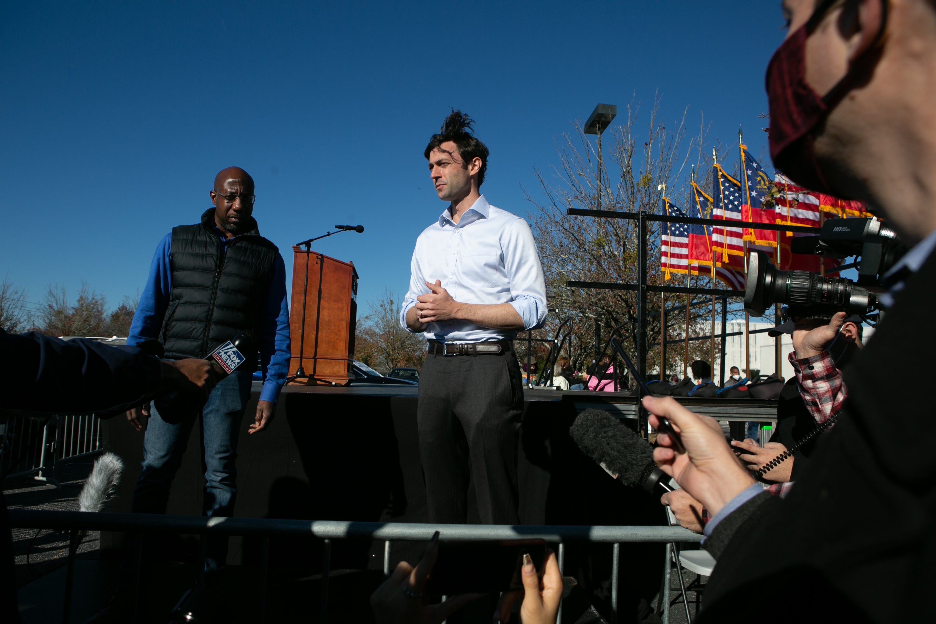 US Senate candidates Raphael Warnock (L) and Jon Ossoff take questions from the press during an outdoor drive-in rally on December 5.