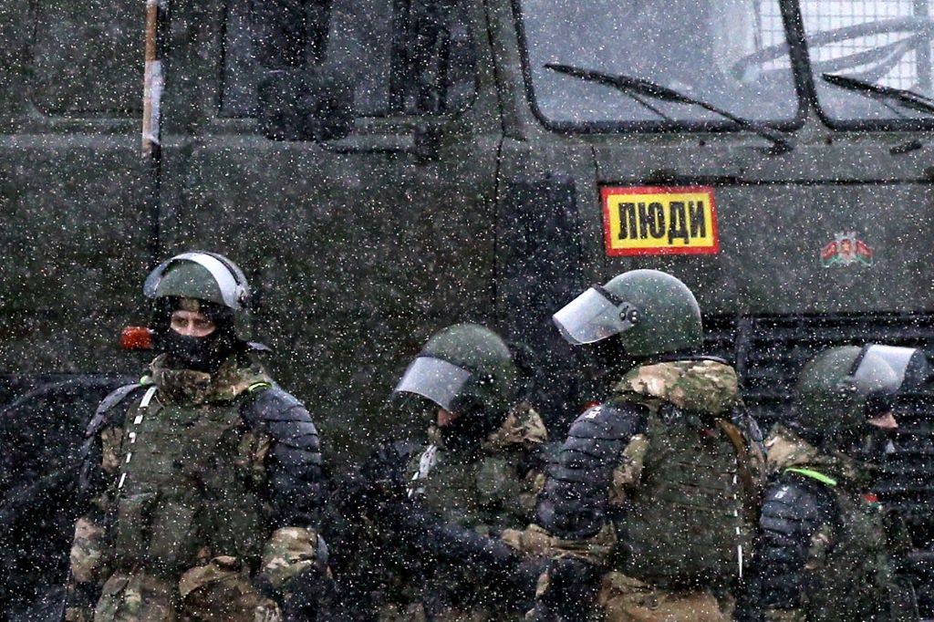 Law enforcement officers stand close to a police van as opposition supporters rally to protest against police violence and the Belarus presidential election results in Minsk