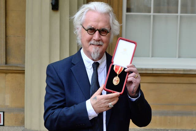 <p>British comedian Billy Connolly poses with his medal after being knighted in 2017</p>