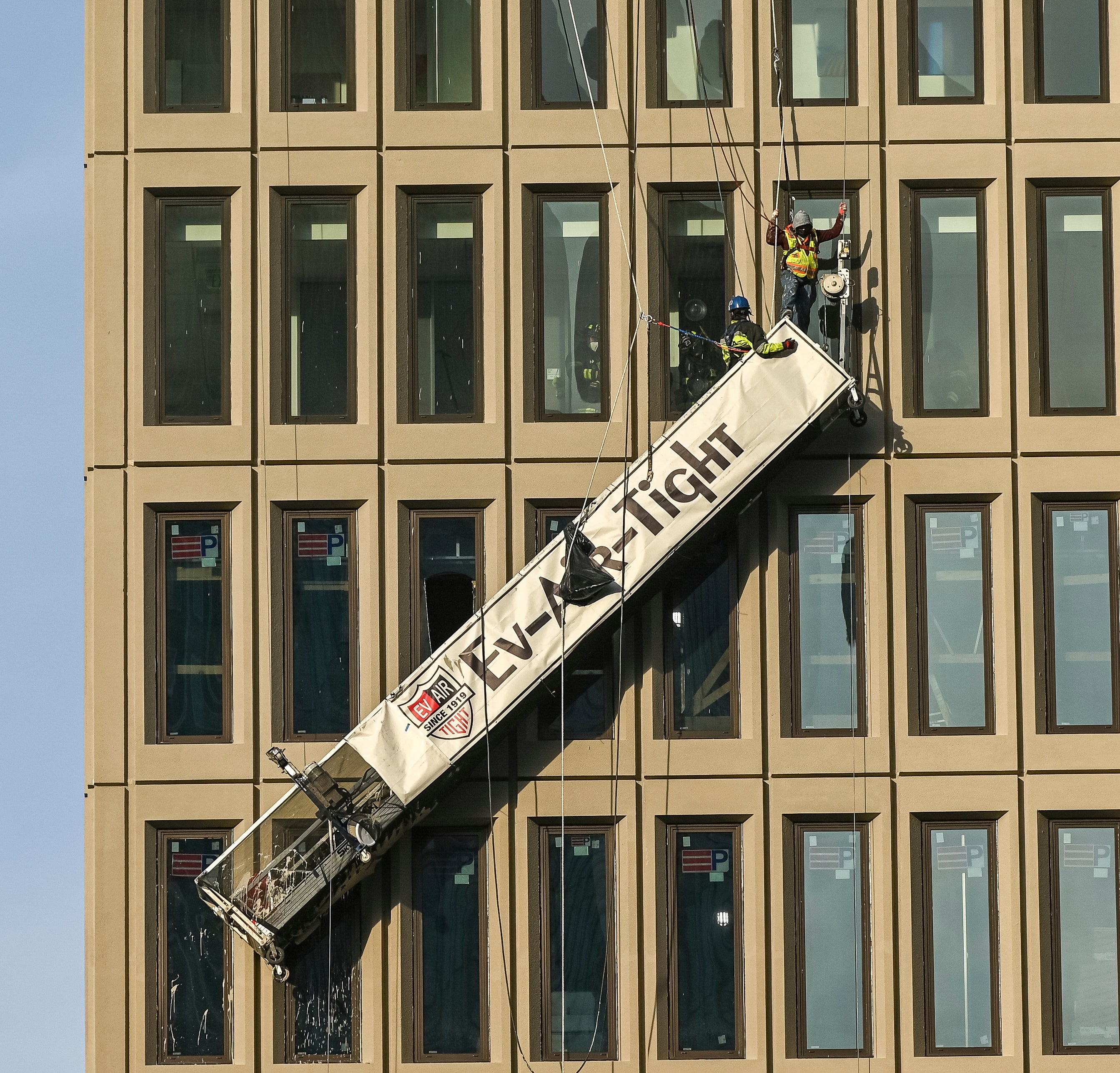 A worker stands on the end of a dangling scaffold as he waits to be rescued following an explosion at Baltimore Gas and Electric's offices, Wednesday, Dec. 23, 2020. Twenty-one of the victims were brought to area hospitals following the explosion with a partial roof collapse. The city’s fire department tweeted that at least nine of the victims were in critical condition, while another was in serious condition. (Jerry Jackson/The Baltimore Sun via AP)