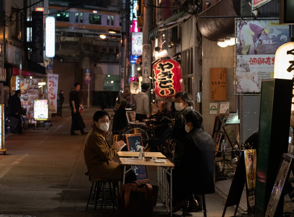 People wearing face masks sit at an outside table of a restaurant on 23 December in Tokyo