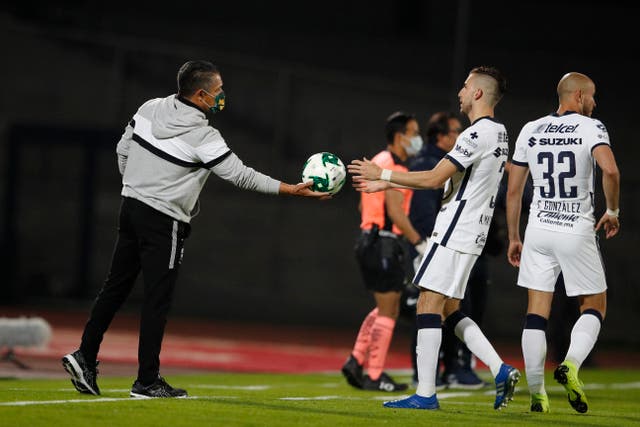 <p>Ignacio Ambriz (izquierda), técnico de León, entrega el balón a Manuel Mayorga, de Pumas, durante el partido de ida de la final de la liga mexicana, el jueves 10 de diciembre de 2020.</p>