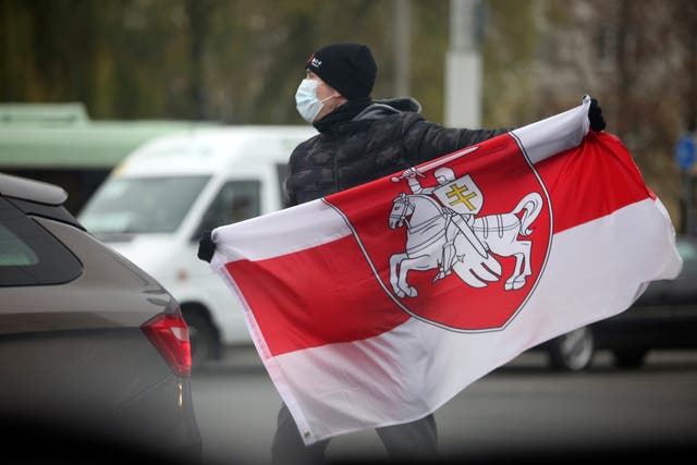 <p>ARCHIVO - En esta fotografía del domingo 22 de noviembre de 2020 un hombre que porta una mascarilla sostiene una bandera bielorrusa durante una manifestación en Minsk, Bielorrusia.&nbsp;</p>