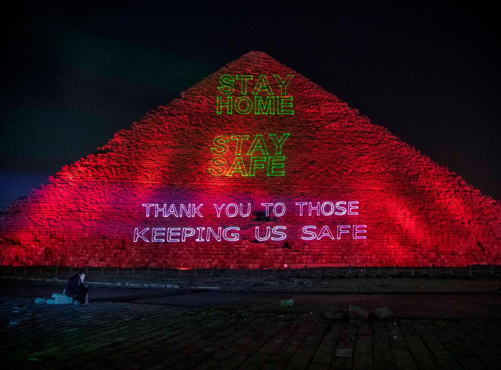<p>Un periodista observa su celular mientras autoridades del ministerio de Antigüedades de Egipto encienden sobre la cara de una de las pirámides de Giza un letrero de apoyo a quienes luchan contra la pandemia de coronavirus, el lunes 30 de marzo de 2020. El mensaje en inglés lee "Quédese en casa y manténgase seguro. Gracias a quienes nos ayudan a mantenernos seguros". </p>