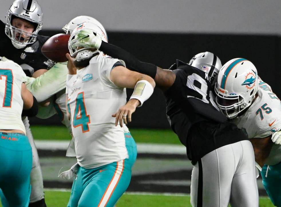 <p>Ryan Fitzpatrick, quarterback de los Dolphins de Miami, es sujetado de la máscara por Arden Key, de los Raiders de Las Vegas, en el encuentro del sábado 26 de diciembre de 2020.</p>