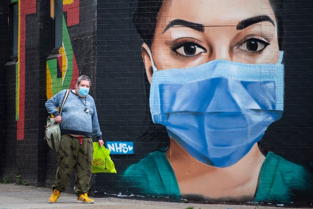 A man in a face mask walks past graffiti by artist Graffiti Life in East London on April 25, 2020 in London, England. 