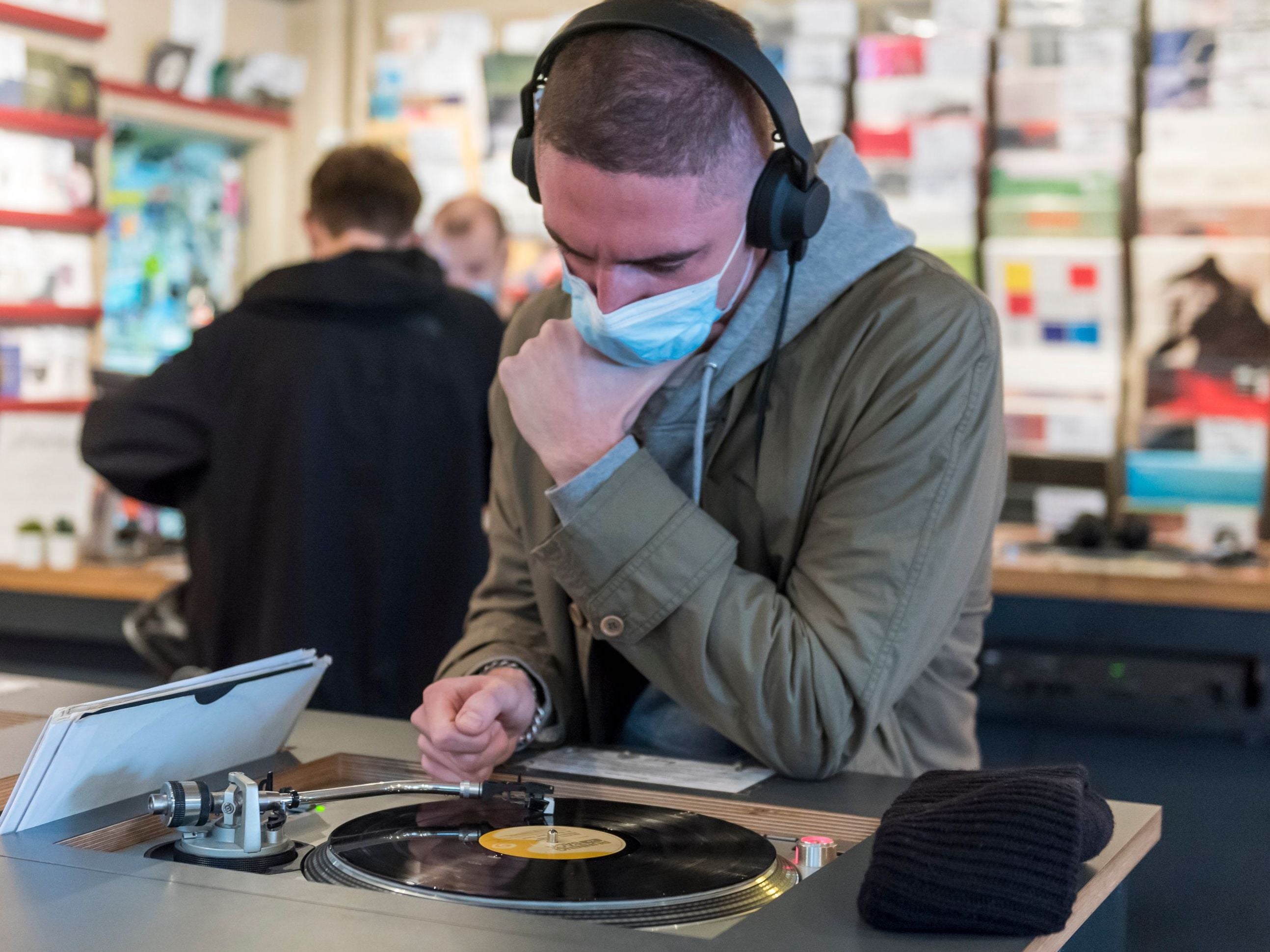 A customer wears a facemask while listening to a vinyl record in Soho, London