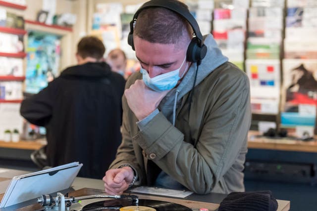 A customer wears a facemask while listening to a vinyl record in Soho, London