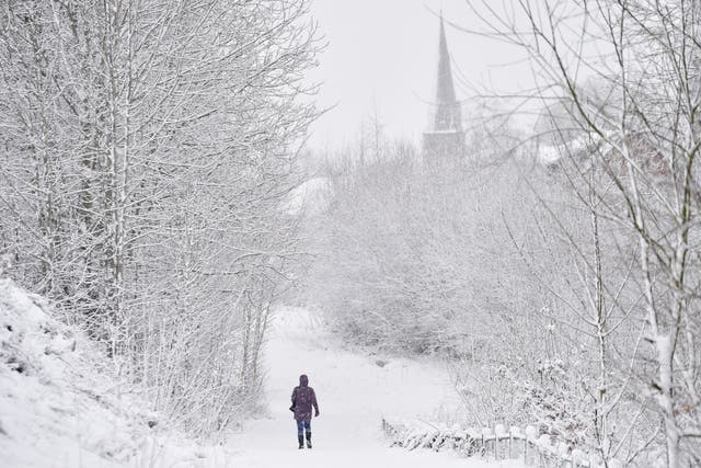 A lady walks in the snow past Silverdale Church on 29 December in Newcastle-Under-Lyme, England