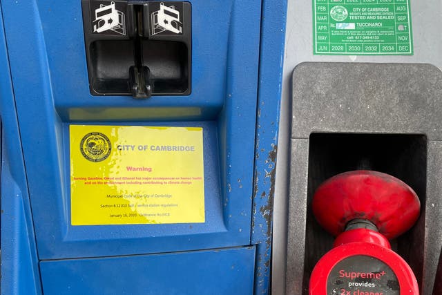 <p>Warning labels on the climate crisis have been attached to gas pumps in Cambridge, Massachusetts</p>