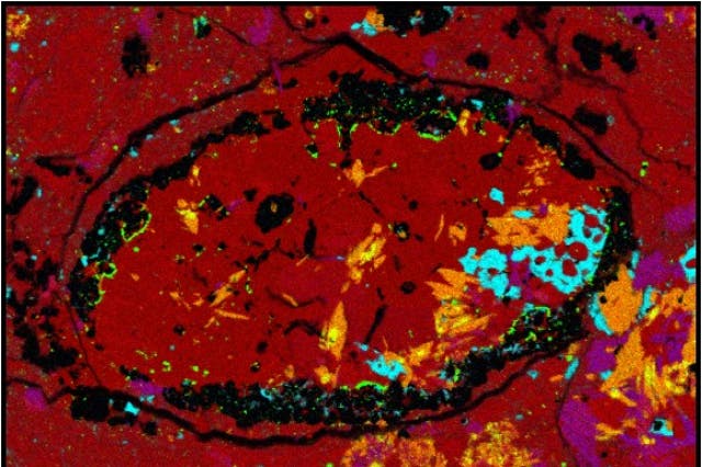This false-color micrograph of the meteoroid sample shows the unexpected amphibole crystals identified in orange