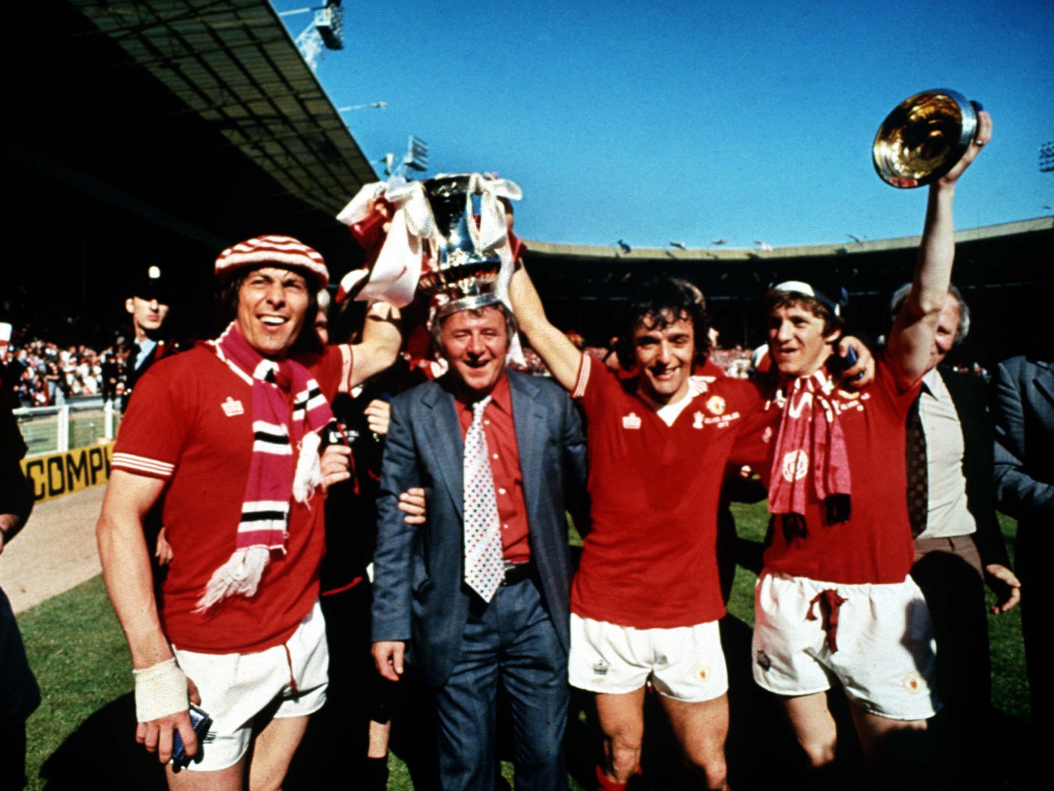 Docherty (second from left) parades the 1977 FA Cup trophy alongside Stuart Pearson, Lou Macari and Gordon Hill