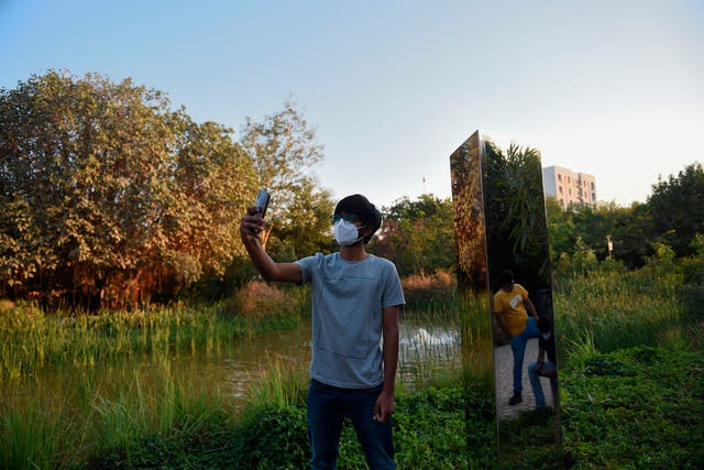 <p>A man takes a selfie with an art installation of a monolith made of steel at Symphony Forest park in Ahmedabad on December 30, 2020</p>