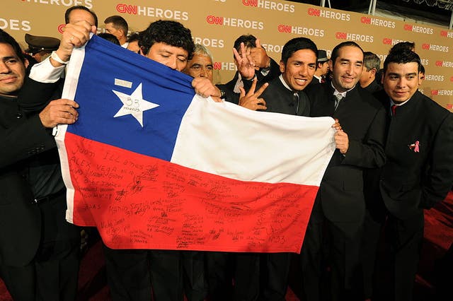 <p>The rescued Chilean miners pose with their national flag in 2010</p>