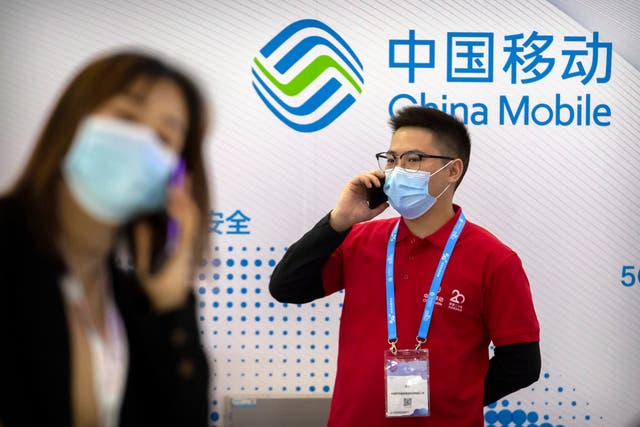 <p>Unas personas cerca de un exhibidor de la empresa china de telecomunicaciones China Mobile en la PT Expo en Beijing, el 14 de octubre de 2020.&nbsp;</p>