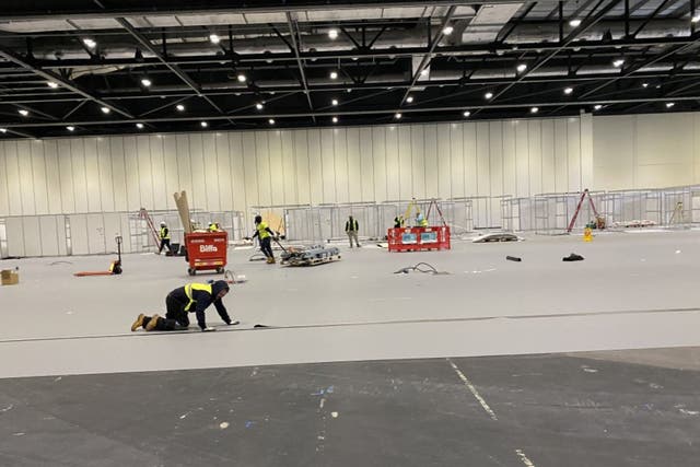 <p>Workmen prepare the NHS Nightingale hospital at the ExCel Centre in east London</p>