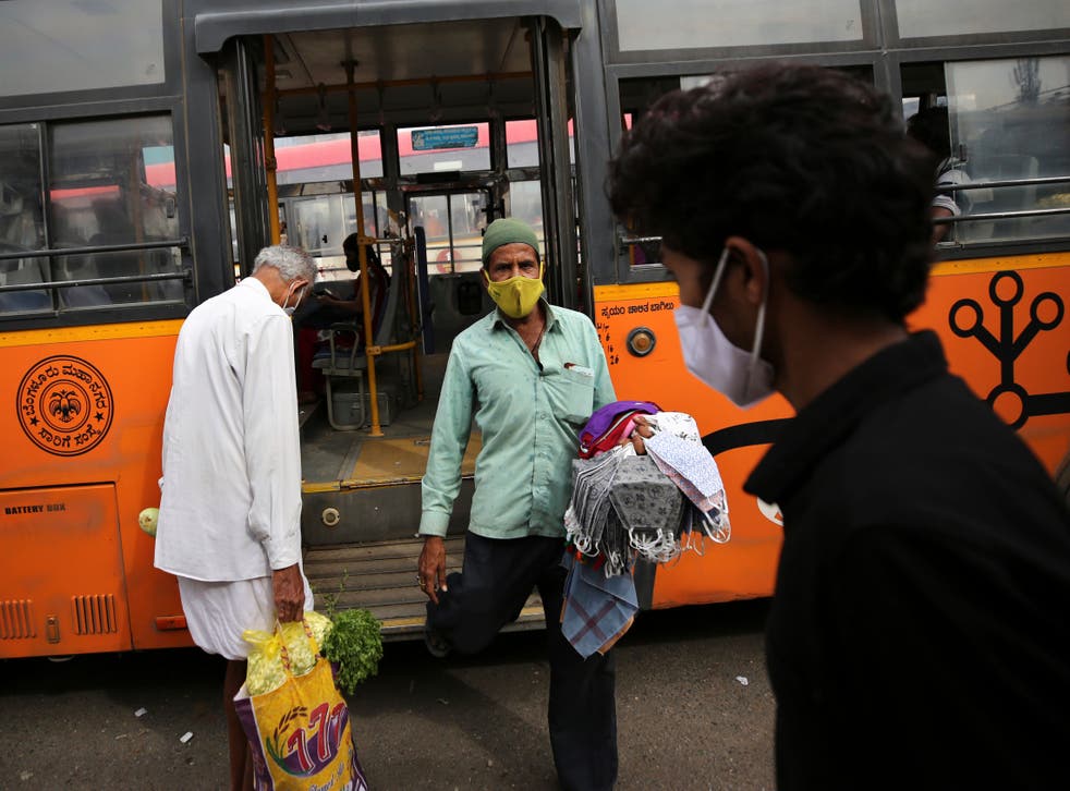 <p>A vendor selling face masks disembarks a bus as he looks for prospective buyers at a bus station in Bengaluru on 5 January, 2021</p>