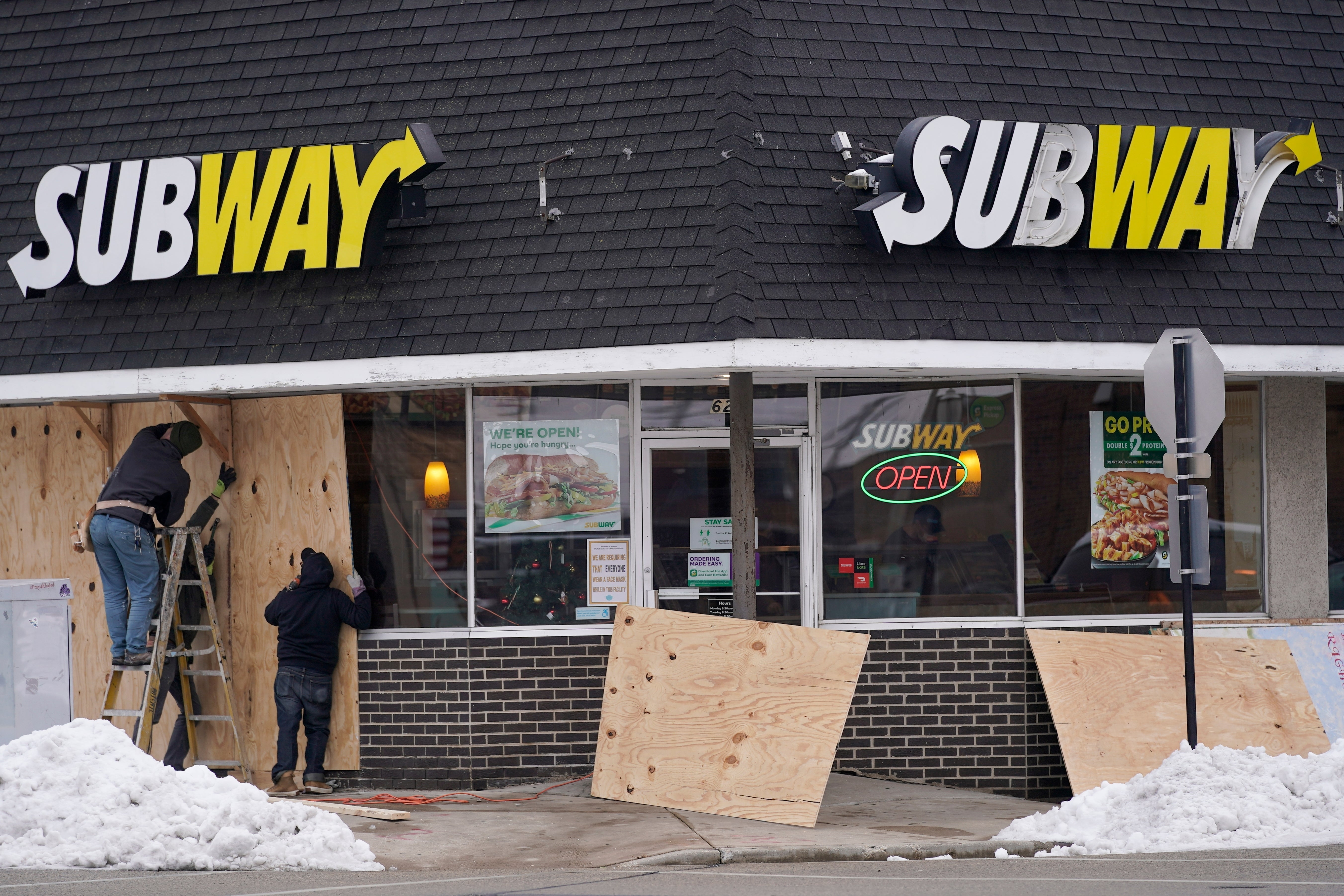Workers board up windows at a Subway on Tuesday, 5 January in Kenosha, Wisconsin ahead of possible unrest