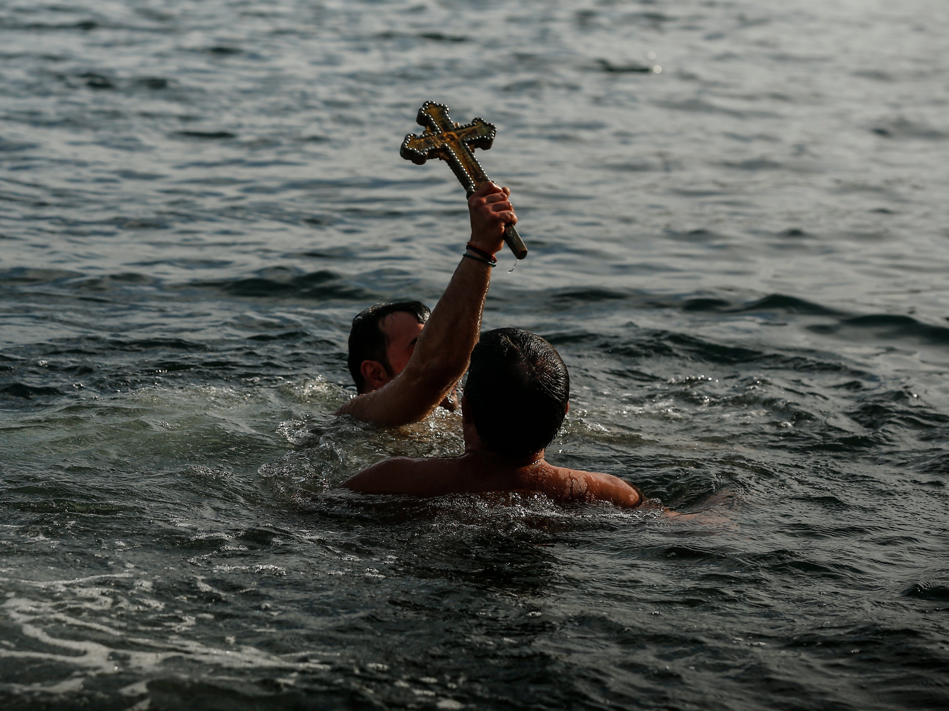 Greek Orthodox faithful, Vasili Kurkcu, holds a wooden crucifix after retrieving it in the Golden Horn during the Epiphany ceremony in Istanbul