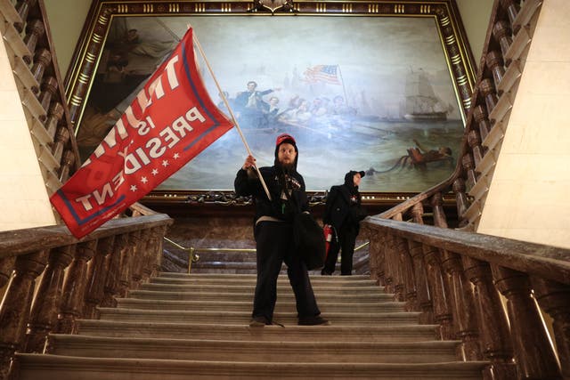 <p>A protester holds a Trump flag inside the US Capitol Building near the Senate Chamber</p>