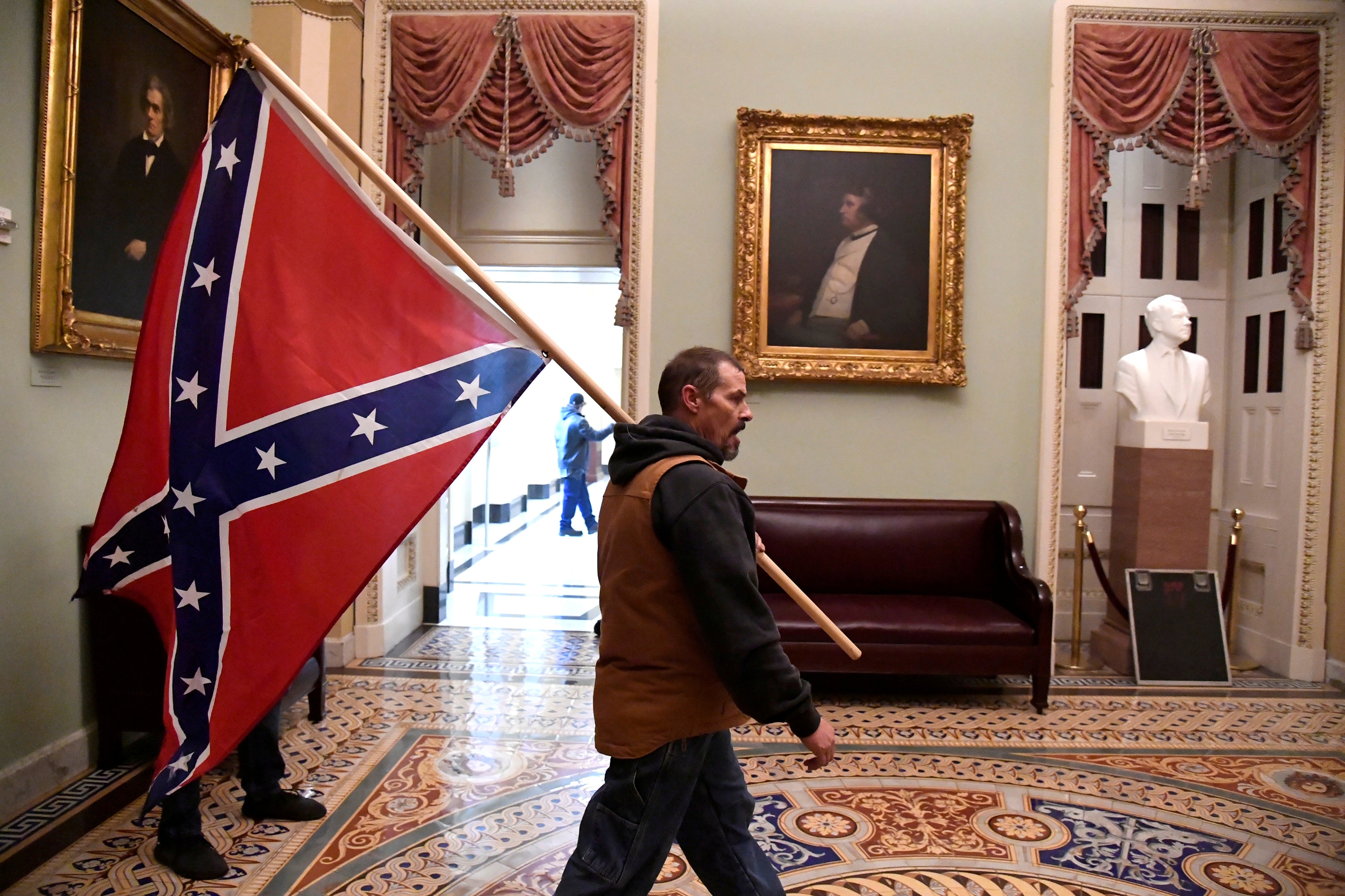 A pro-Trump rioter carries a Confederate flag through the halls of the Capitol on Wednesday