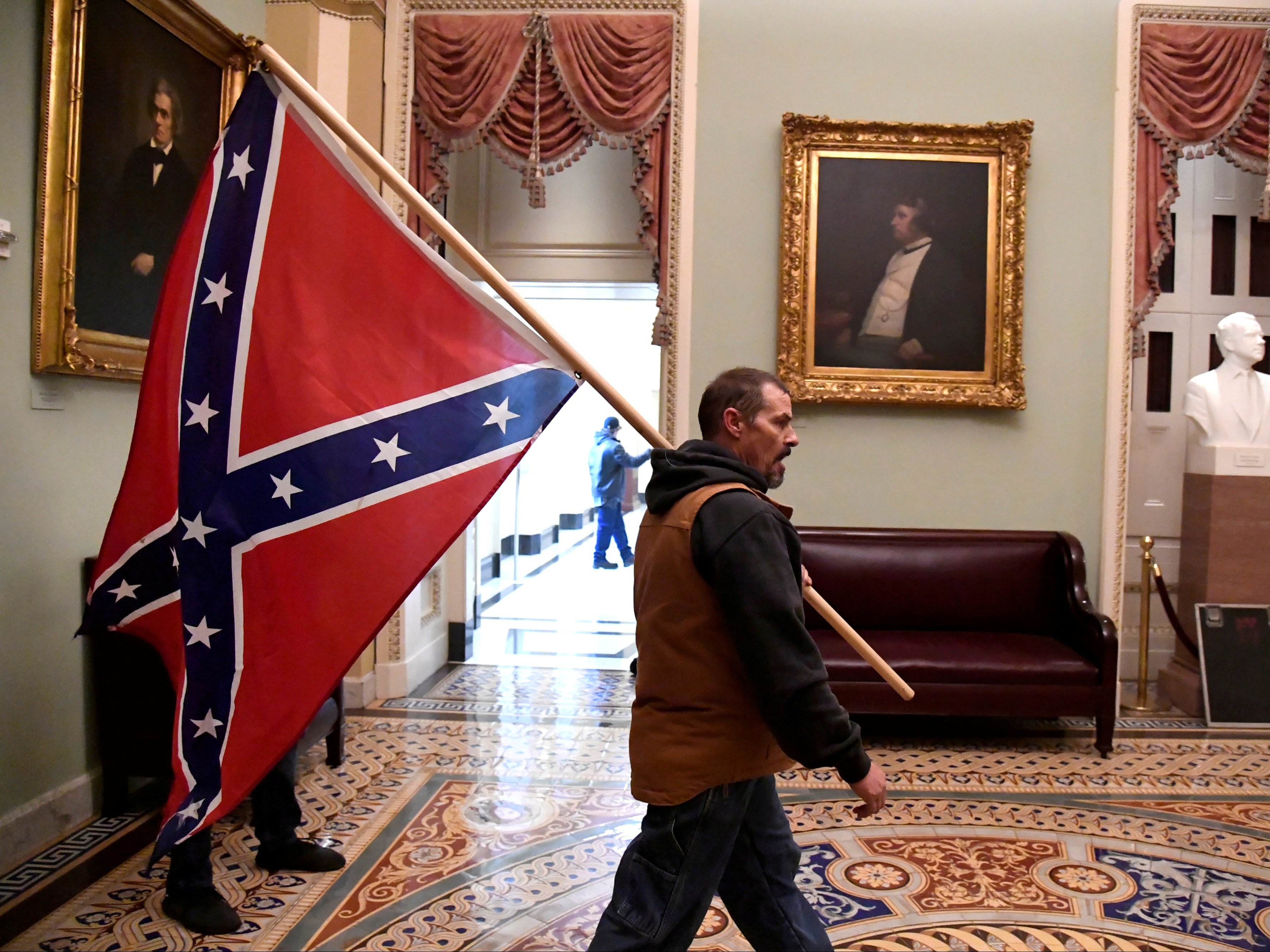A supporter of President Donald Trump carries a Confederate battle flag on the second floor of the U.S. Capitol near the entrance to the Senate after breaching security defences, in Washington, on 6 January 2021