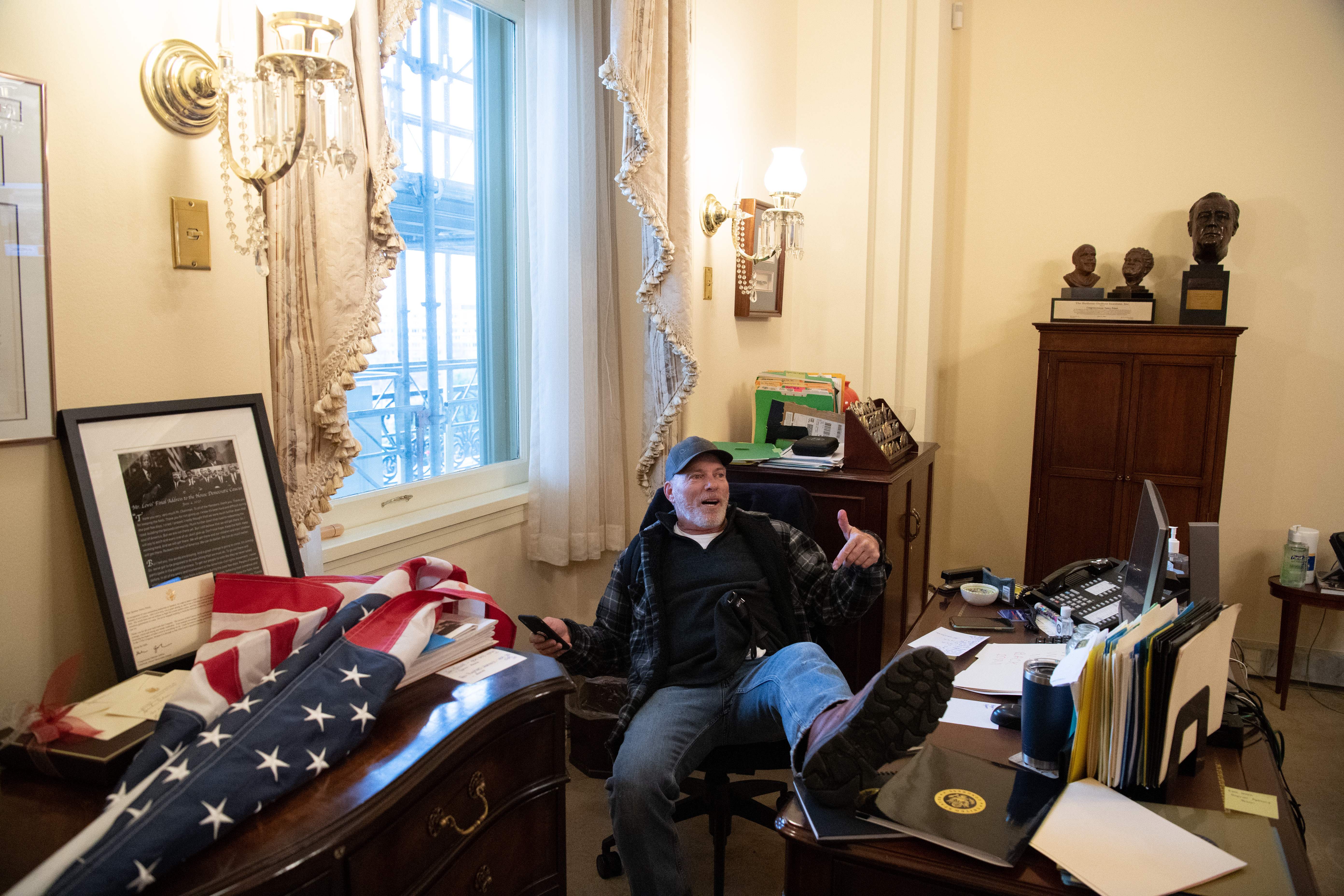 Richard Barnett, a supporter of US President Donald Trump sits inside the office of US Speaker of the House Nancy Pelosi as he protests inside the US Capitol