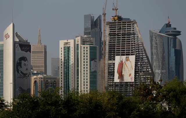 <p>Images of the Emir of Qatar hang on towers in Doha</p>