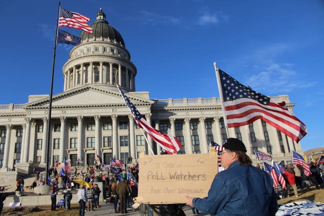 An attendee to Salt Lake City’s “Save America” rally holds up a sign in front of the Utah Capitol with the message “In case of poll watchers, tape over windows” on Wednesday, Jan. 6, 2021.