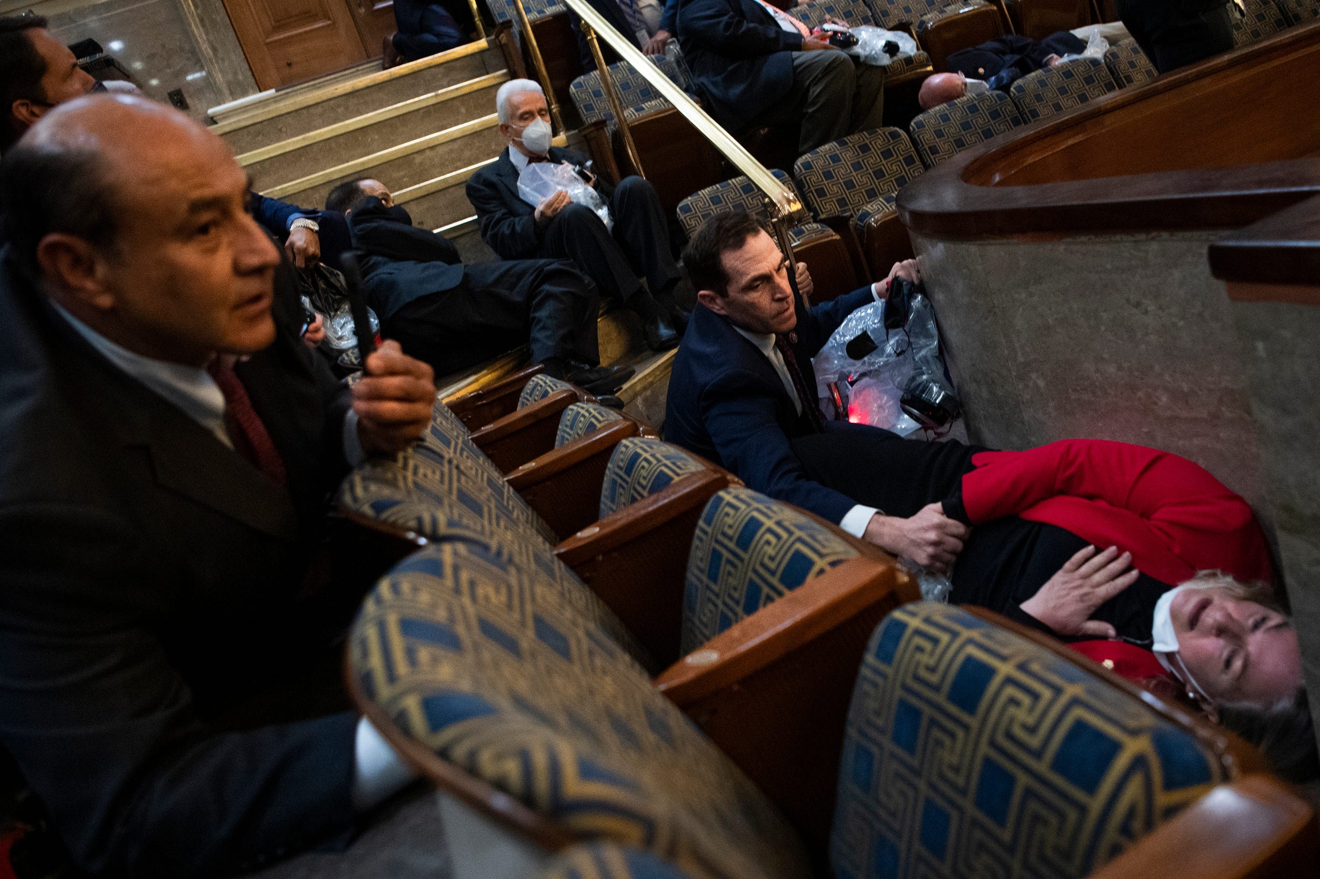 Rep. Jason Crow, D-Colo., comforts Rep. Susan Wild, D-Pa., while taking cover as protesters disrupt the joint session of Congress to certify the Electoral College vote