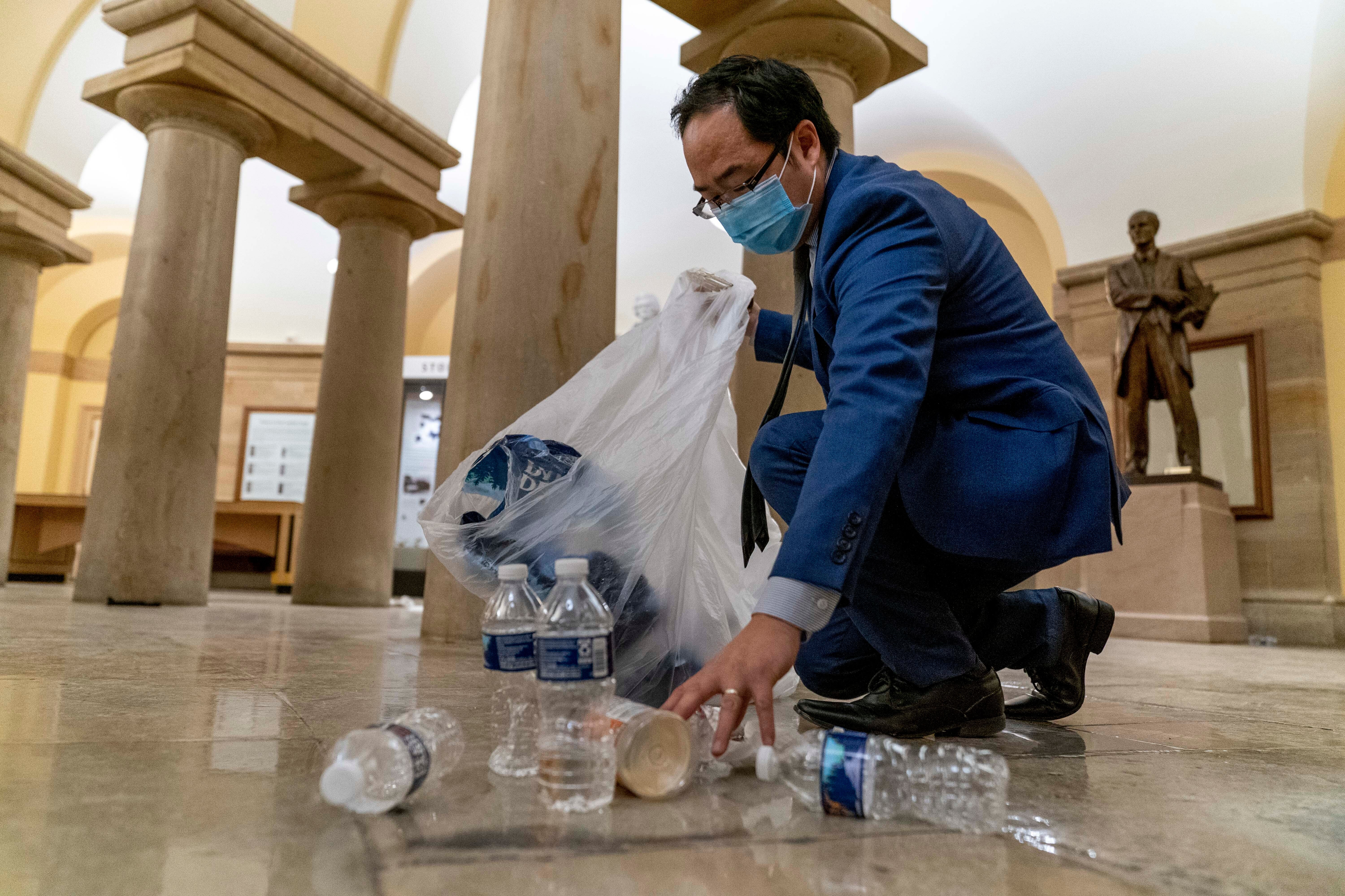 Representative Andy Kim cleans up debris and trash strewn across the floor in the early morning hours of Thursday