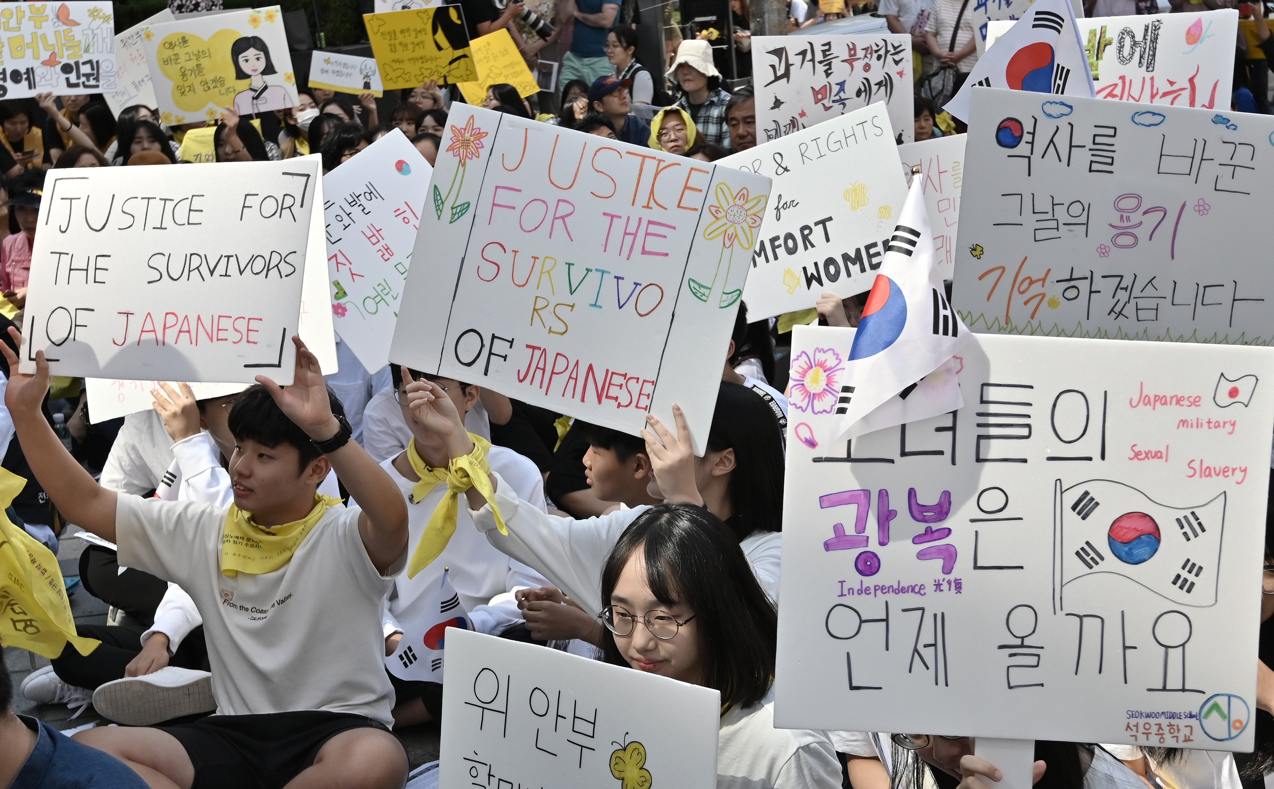 File Image: Supporters of former ‘comfort women’, who were forced to serve as sex slaves for Japanese troops during World War II, hold placards during a demonstration demanding the Japanese government's formal apology near the Japanese embassy in Seoul on 18 September 2019
