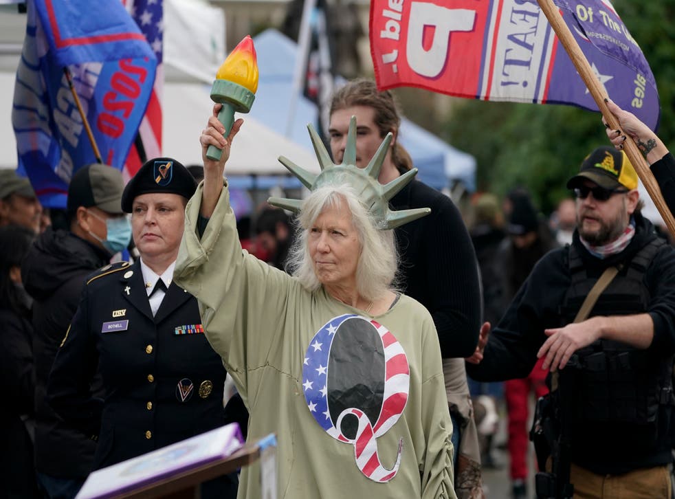 <p>A person dressed as Lady Liberty wears a shirt with the letter Q, referring to QAnon, as protesters take part in a protest, Wednesday, Jan. 6, 2021</p>