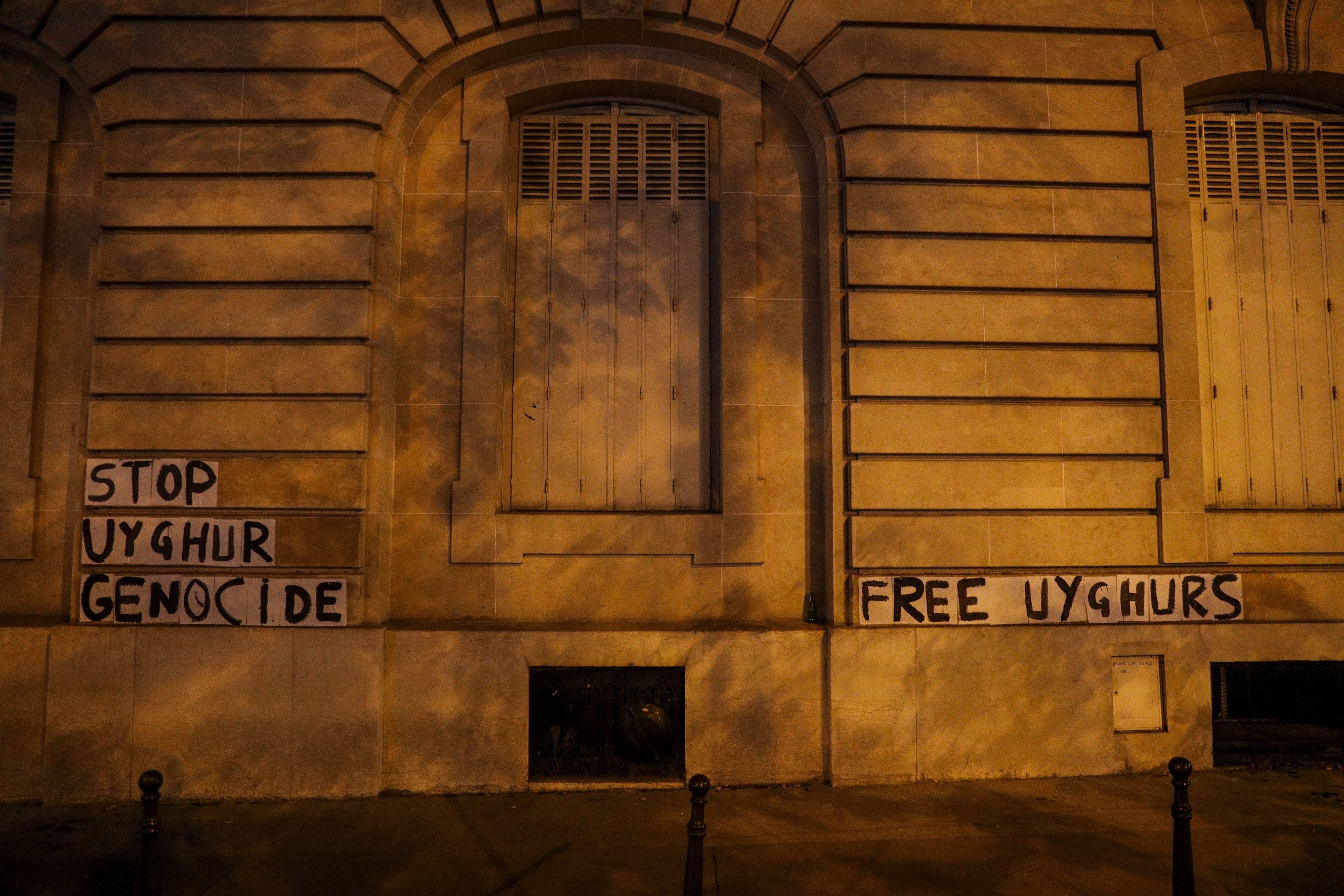 File Image: A picture taken on 29 July 2020 shows banners pasted by members of a collective against violence towards women in support of the Uighur population on a wall on the George V avenue, near China's Embassy in Paris