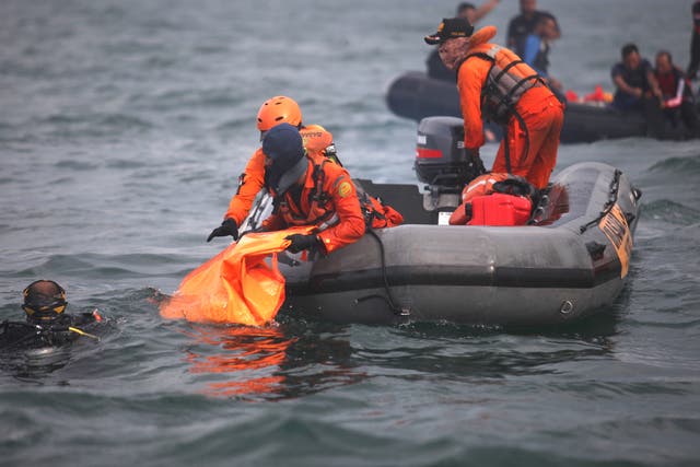 Divers bringing up bags filled with debris and body parts to a search and rescue boat from Sriwijaya Air flight SJ182 at Tanjung Priok port, north of Jakarta