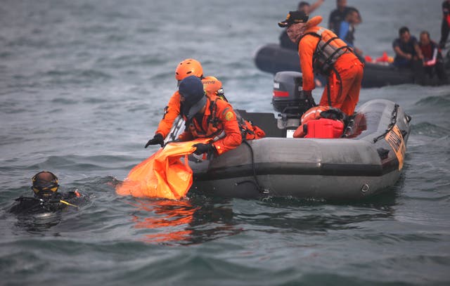 Divers bringing up bags filled with debris and body parts to a search and rescue boat from Sriwijaya Air flight SJ182 at Tanjung Priok port, north of Jakarta