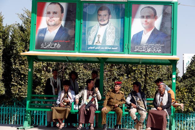 <p>Armed militiamen and supporters of the Houthi movement sit under portraits of top Houthi leaders</p>