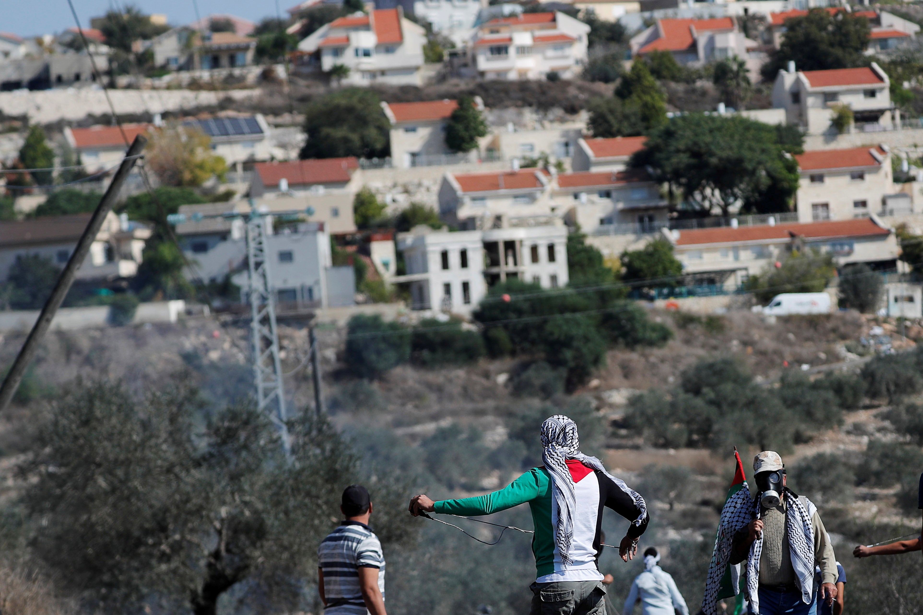 Palestinian demonstrators stand in front of a Jewish settlement during a protest in the Israeli-occupied West Bank