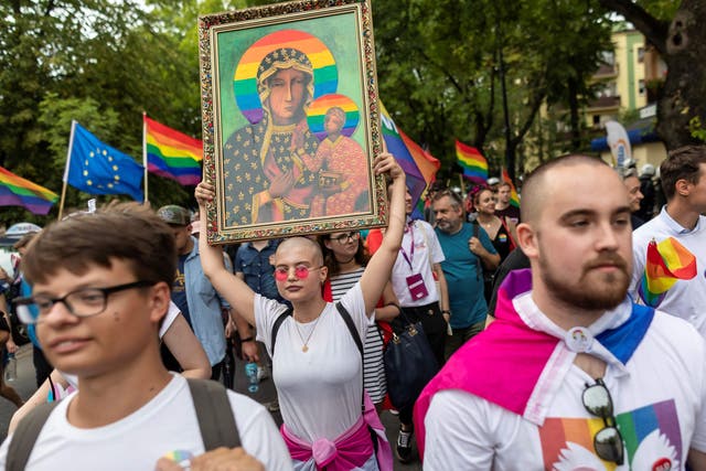 A woman holds a frame depicting the Virgin Mary with a rainbow halo during the first gay pride organised in Plock, central Poland, in 2019