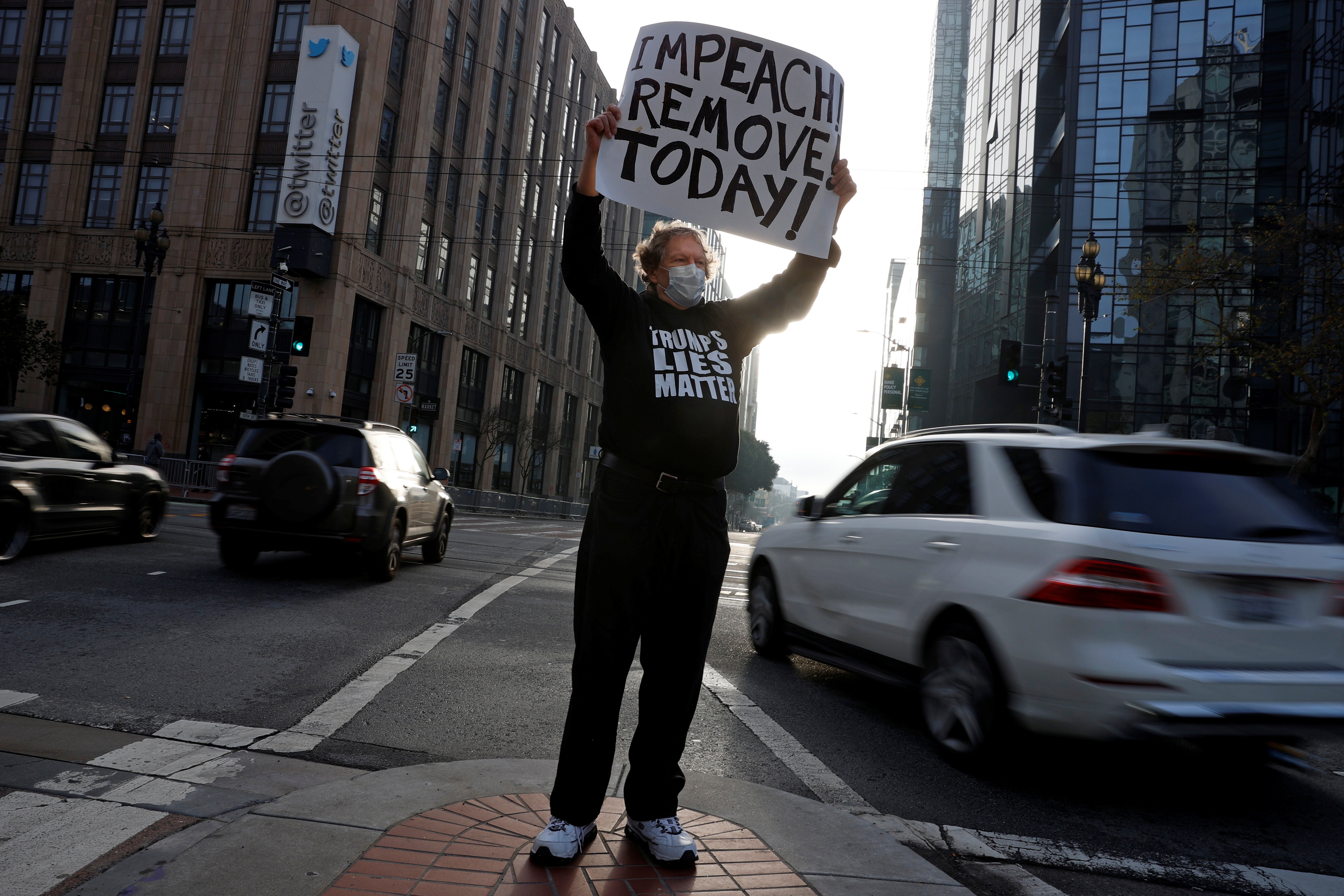 <p>Kenneth Lundgreen holds a sign in counter-protest during what was supposed to be a pro-Trump demonstration outside Twitter headquarters in San Francisco</p>