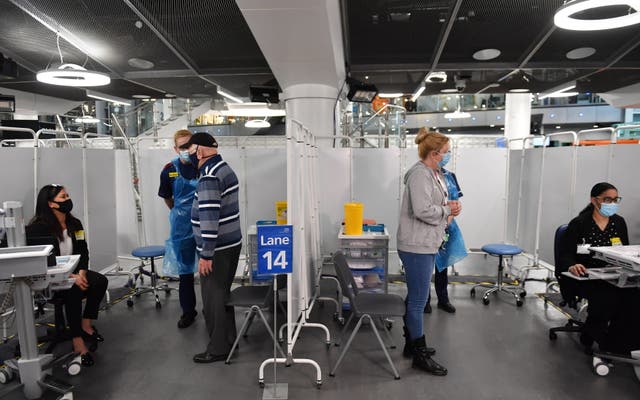 Members of staff talk to patient before administering an injection of a Covid-19 vaccine  at the NHS vaccine centre that has been set up at the Millennium Point centre in Birmingham