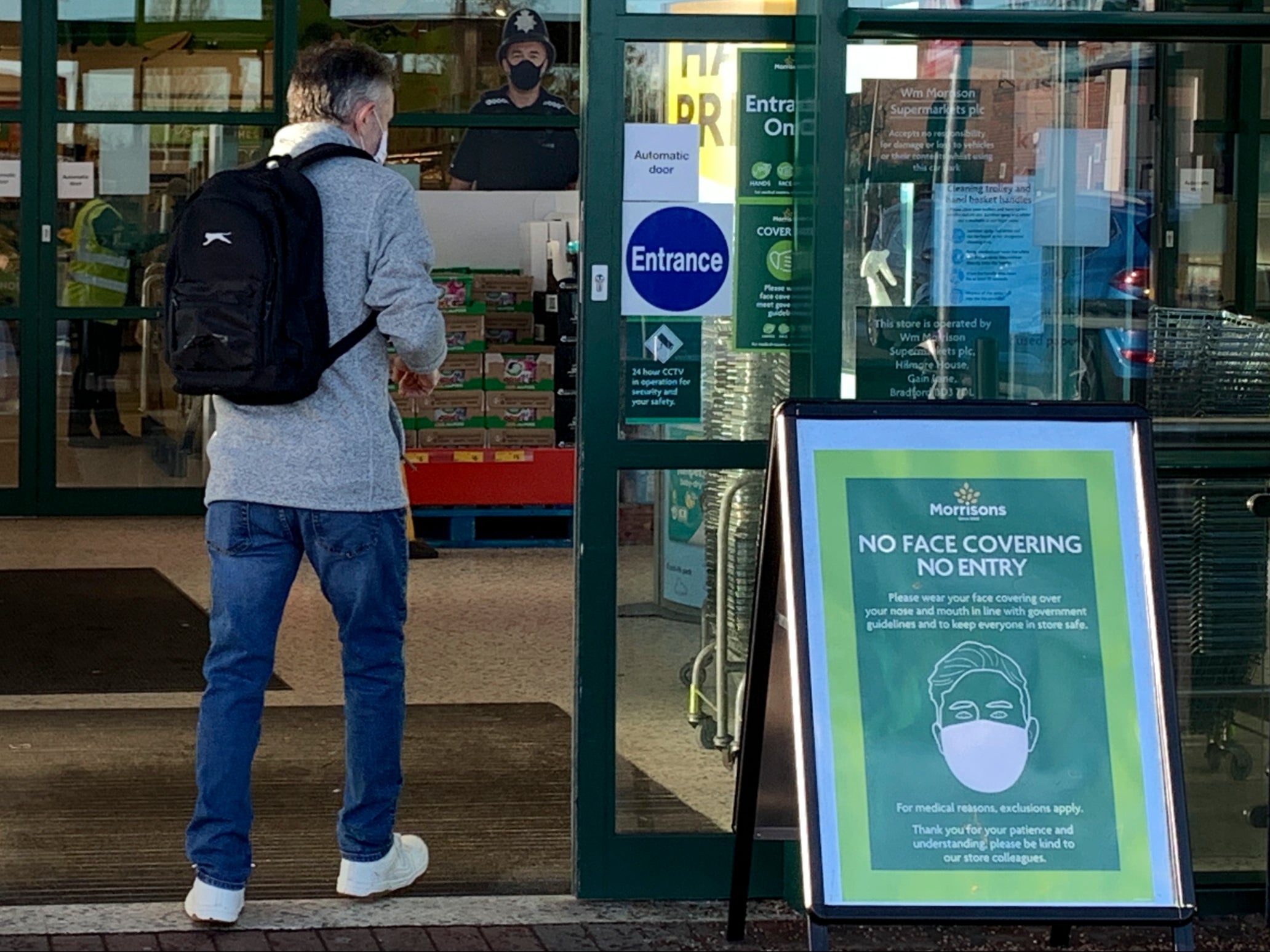 A sign at the entrance informs customers that they must wear a face mask because of the coronavirus pandemic at a Morrisons supermarket in Ellesmere Port, northwest England